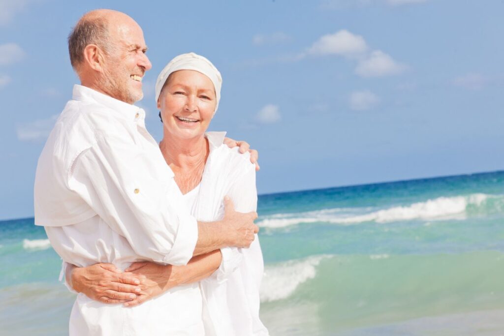 Älteres Paar lächelt am Strand – Symbolbild für Urlaub trotz Demenz und eine Auszeit für Angehörige