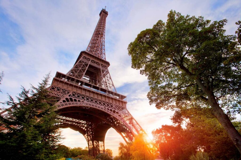 Besucherrekord: Frankreich ist mit 102 Millionen Gästen beliebtestes Urlaubsziel 2025 Eifelturm in Paris in Froschperspektive mit baum und sonne