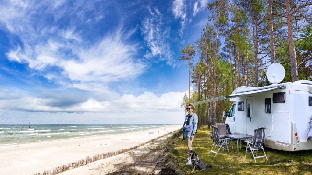 Eine Frau mit Hund, die mit dem Wohnmobil unterwegs ist, genießt den Strand an der Ostsee.
