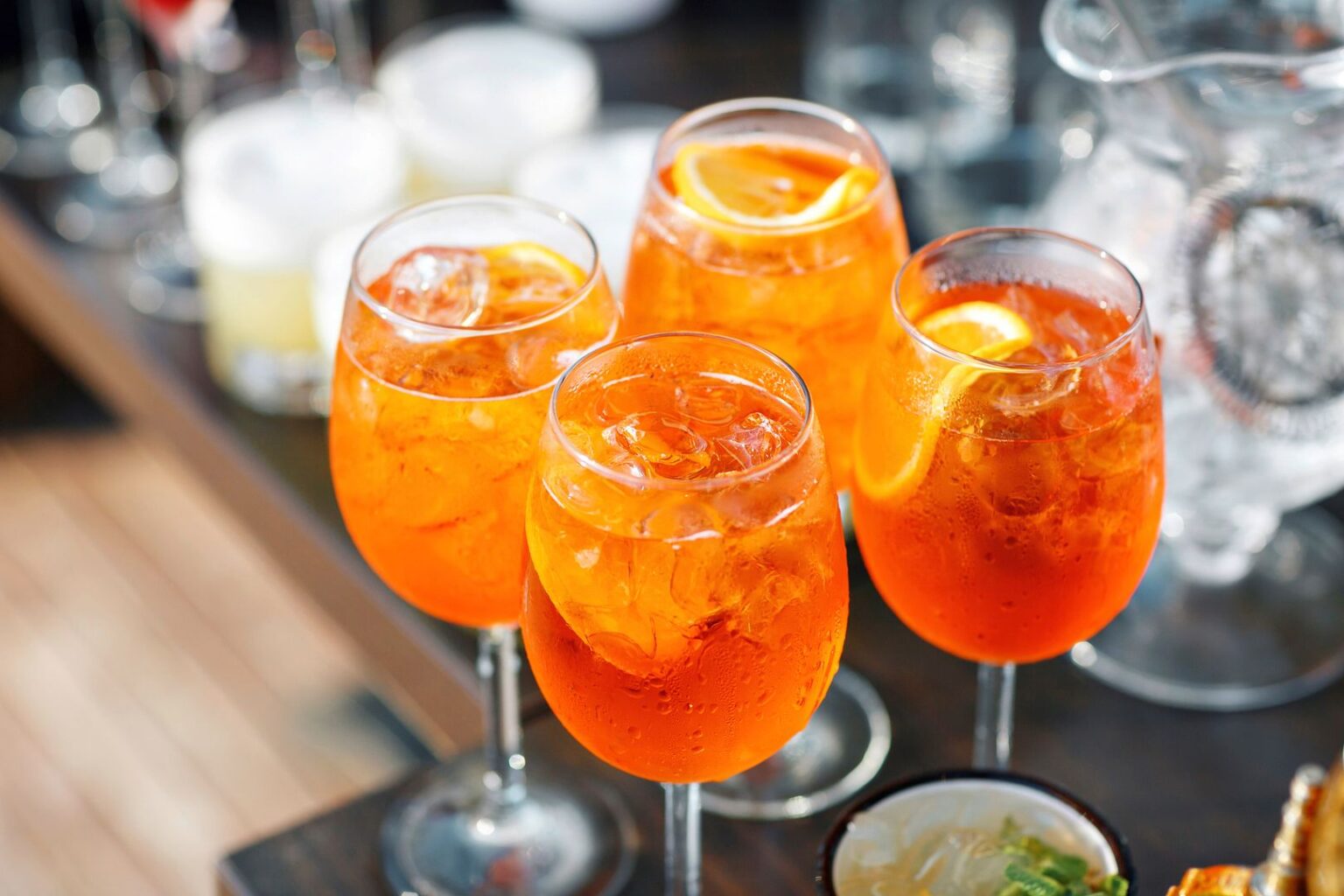 Aperol Spritz & Sonnenschein: Hier sparen Urlauber beim Anstoßen Aperol Spritz Gläser an einer Bar