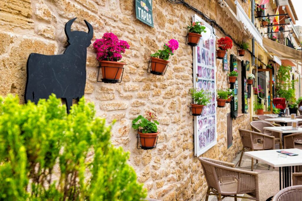 Häuserfassade mit Blumen und Stier einer Restaurantterrasse in Spanien