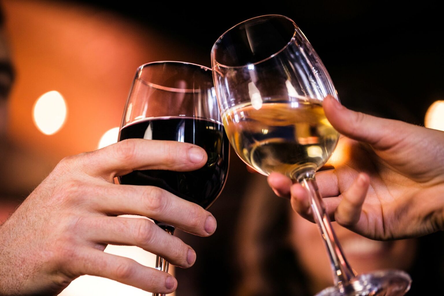 Nahaufnahme Rotwein-und Weißweinglas beim Anstoßen