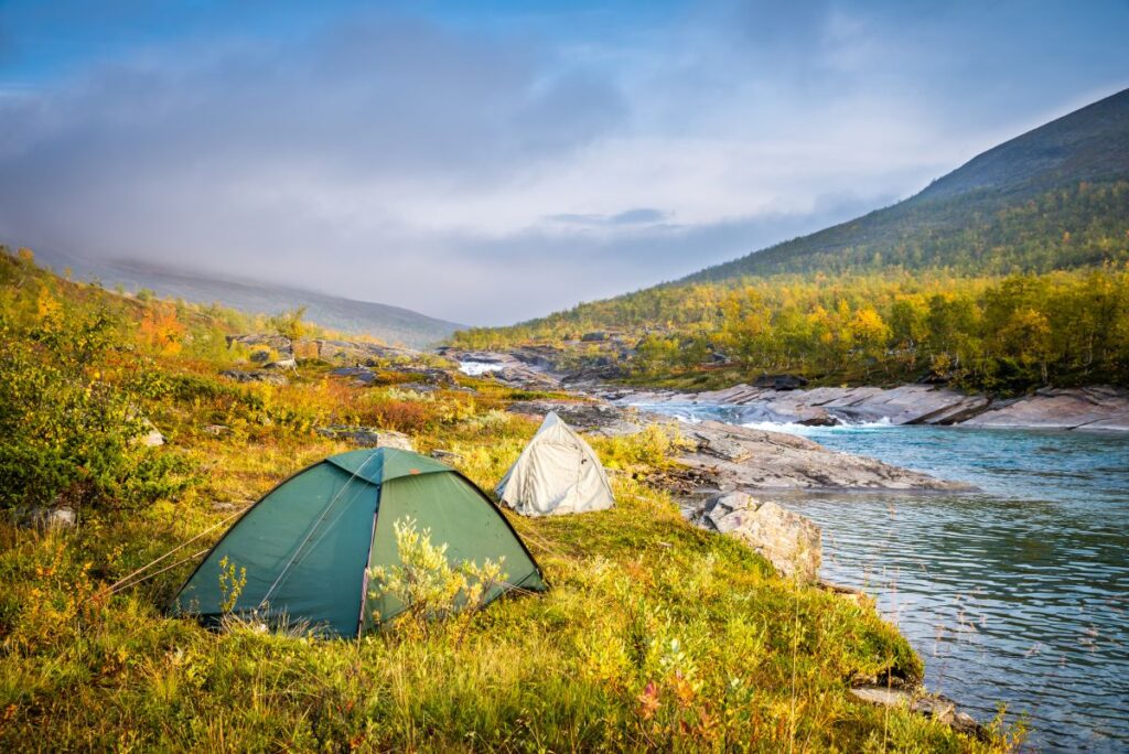Schweden-Urlaub: Auswärtiges Amt warnt vor Diebstählen Zelten in der Morgendämmerung in idyllischer Flusslandschaft des Royal Trails
