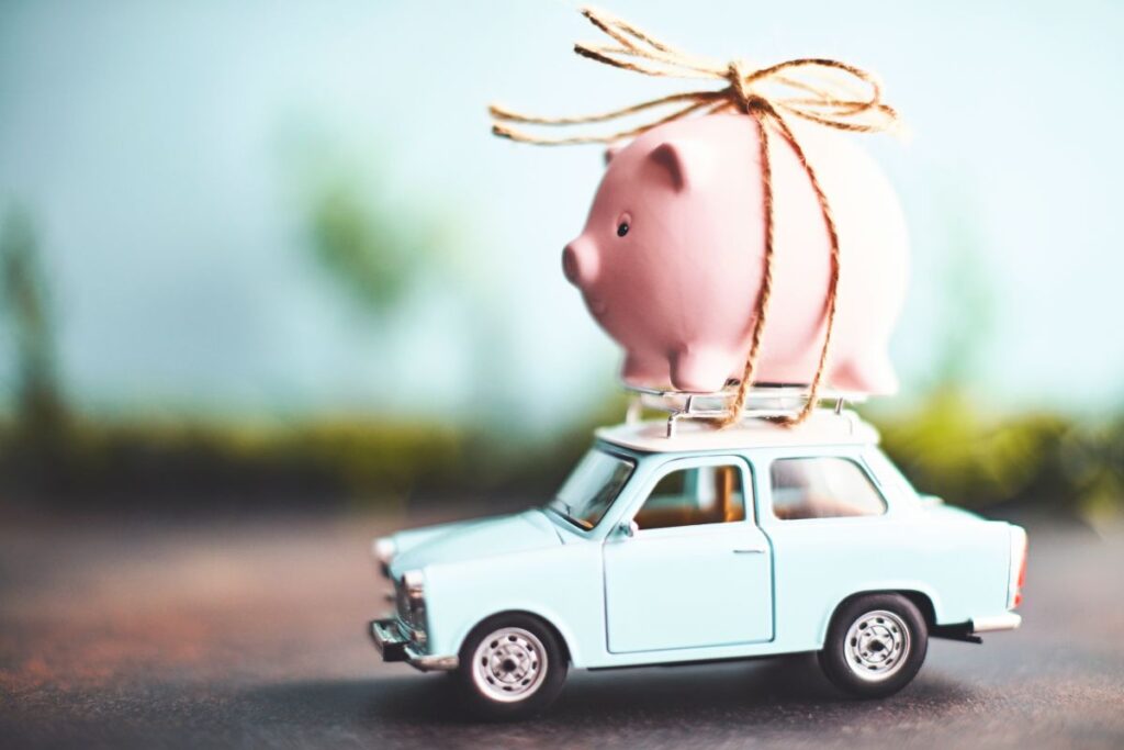 Preisvergleich Urlaubskosten: Wo Sie am Mittelmeer noch sparen und welche Länder Ihr Budget sprengen Ein rosafarbenes Sparschwein ist auf einem alten Modellauto mit Paketband festgemacht. Symbolbild für die Sparmöglichkeiten in bestimmten Urlaubsländern.