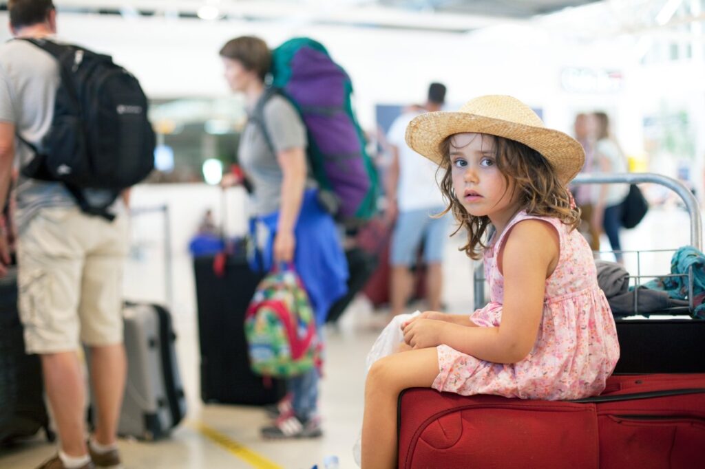 Kind am Flughafen sitzt auf einem Koffer