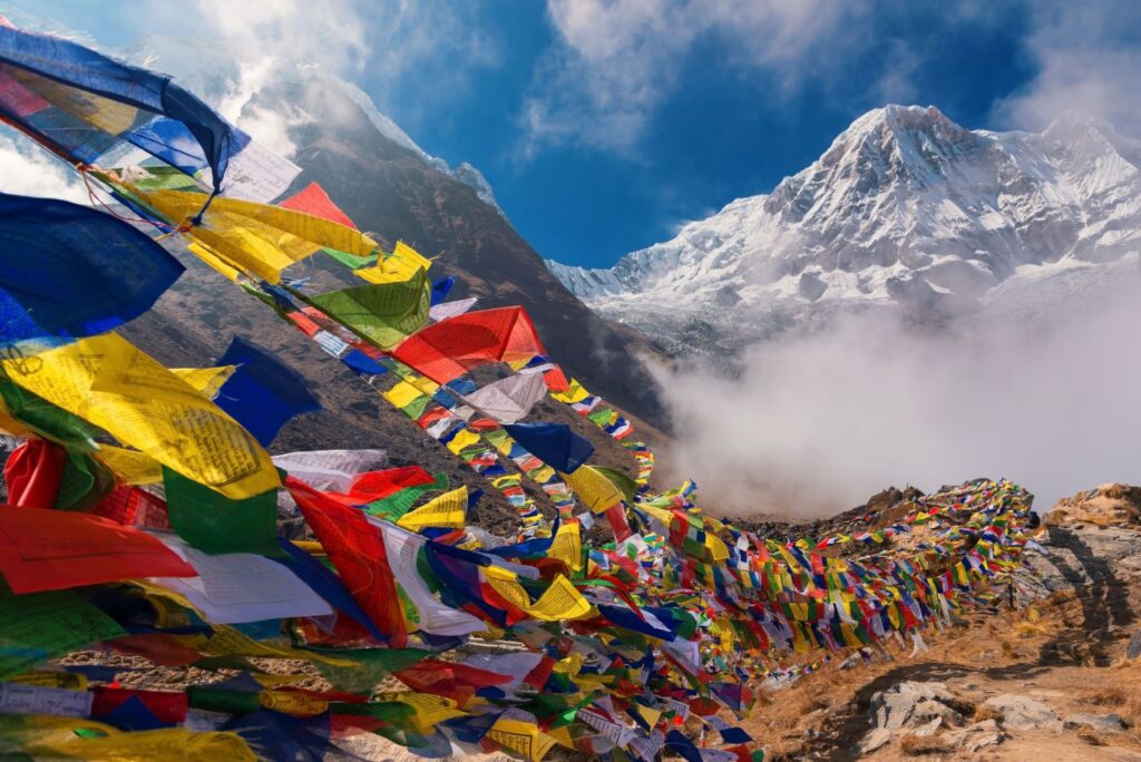 Gebetsfahnen säumen den Weg vor der majestätischen schneebedeckten Bergkulisse des Himalaya in Nepal.